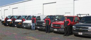 Workers standing beside parked company vehicles