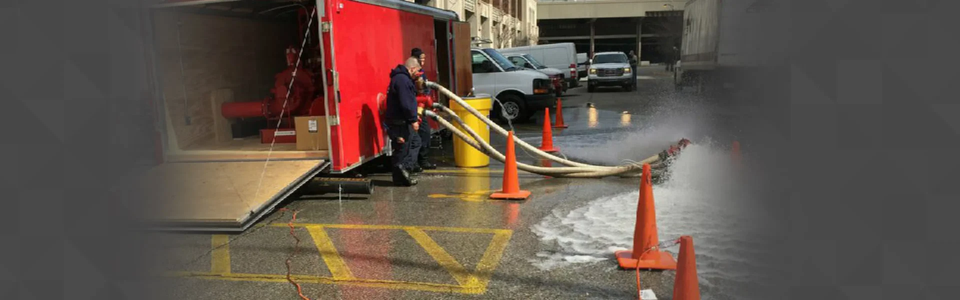 Workers handling water hoses near trailer